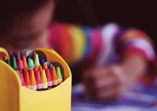 école: une petite fille dessine au crayon gras